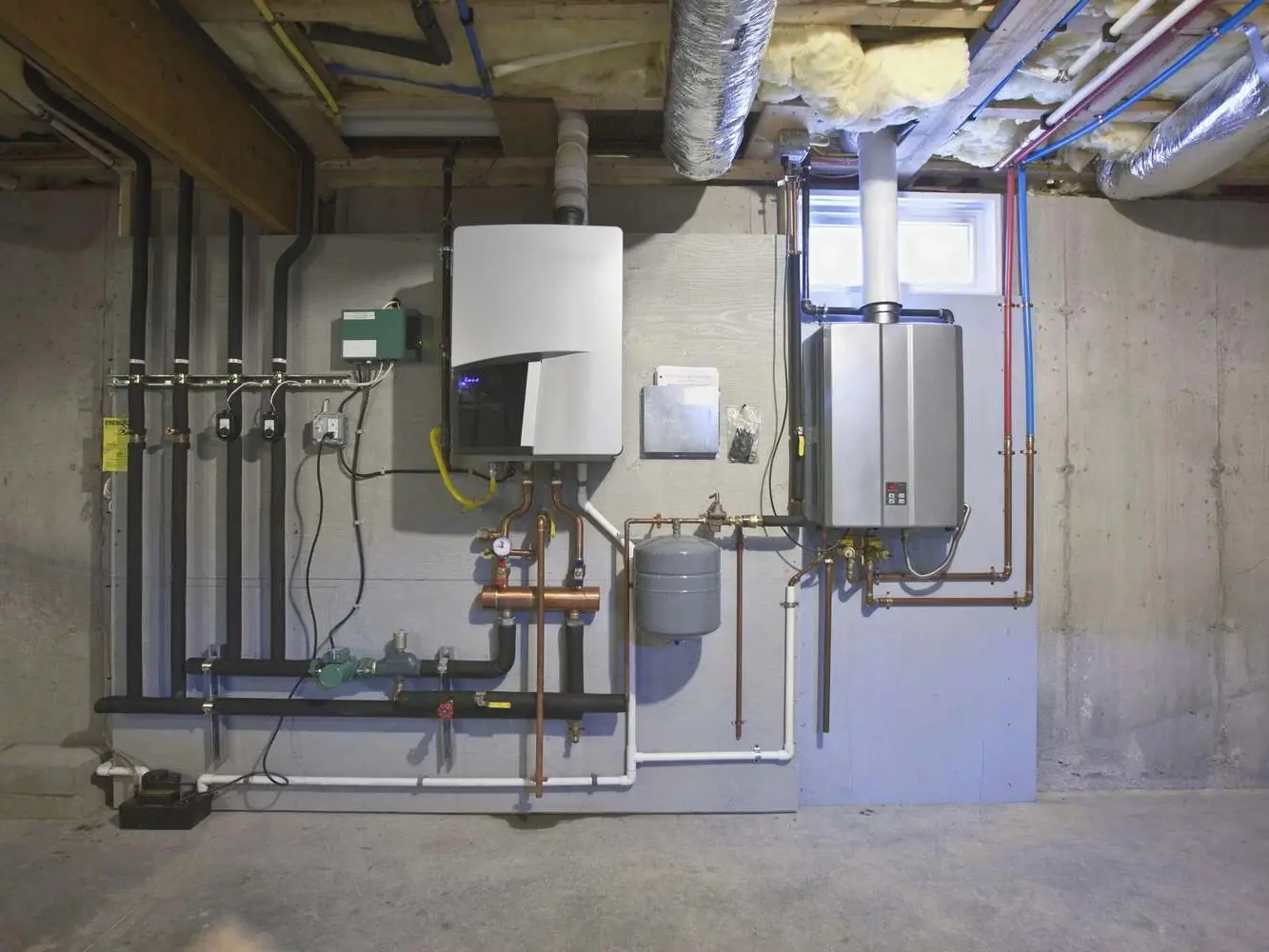 Tankless water heater installed on a basement wall with copper piping